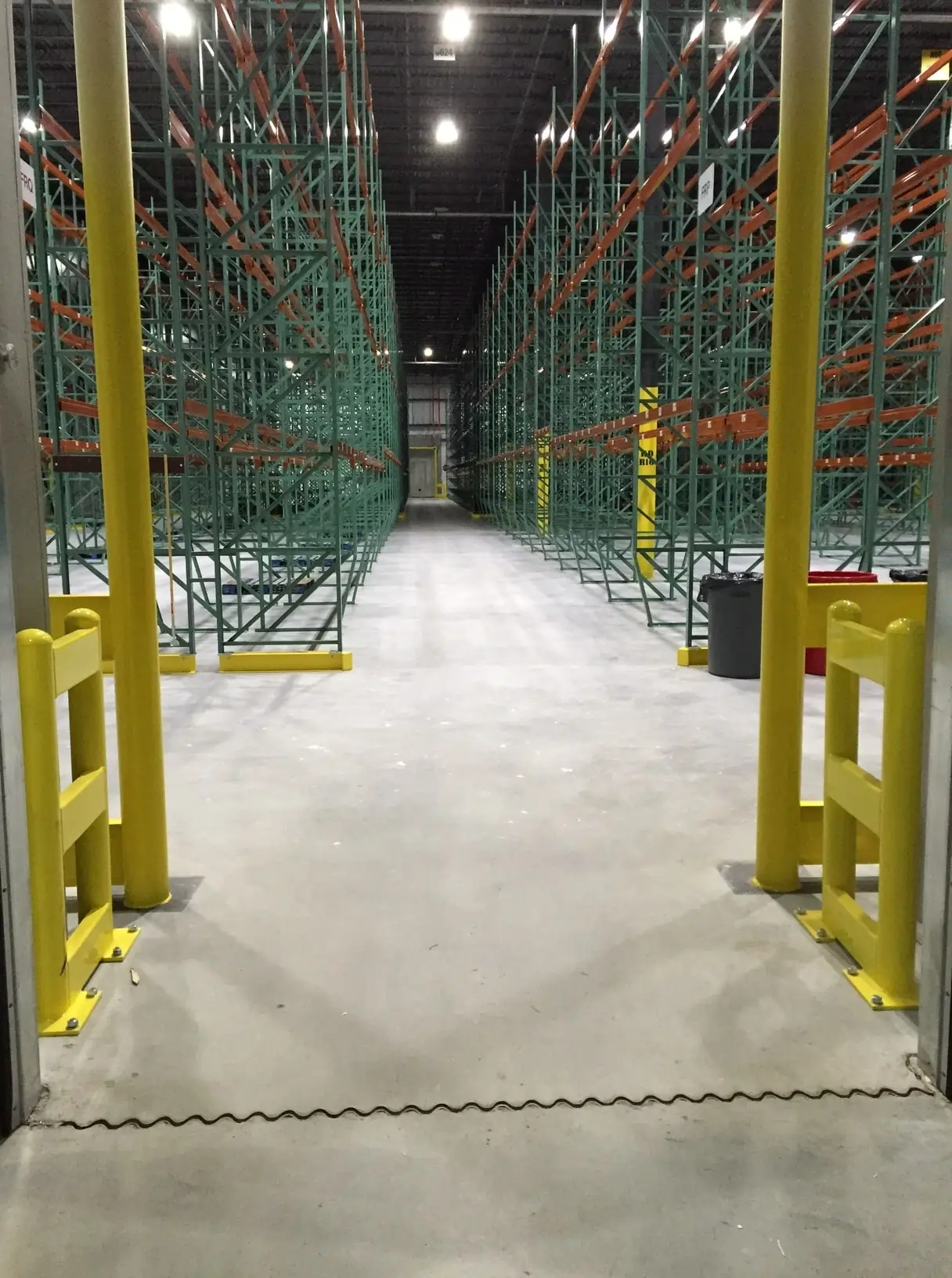 High-performance industrial concrete floor with joint system installation in a warehouse featuring orange pallet racking, showcasing Conarmor's durable concrete solutions for demanding commercial environments.